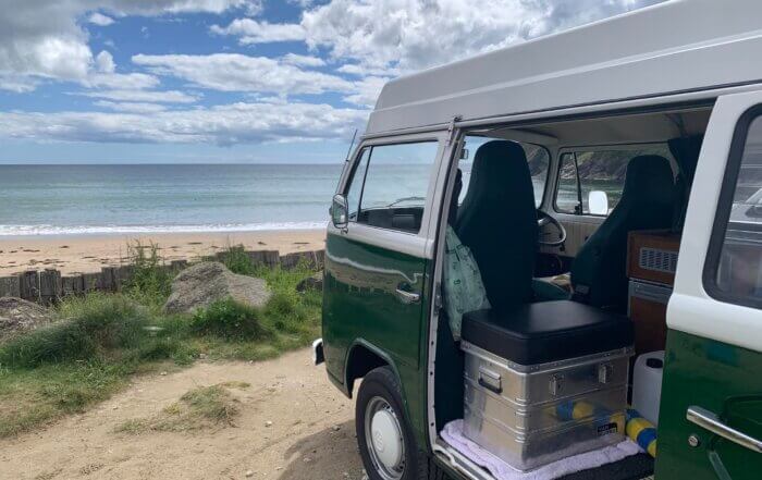 Green VW campervan looking out to sea from beach edge